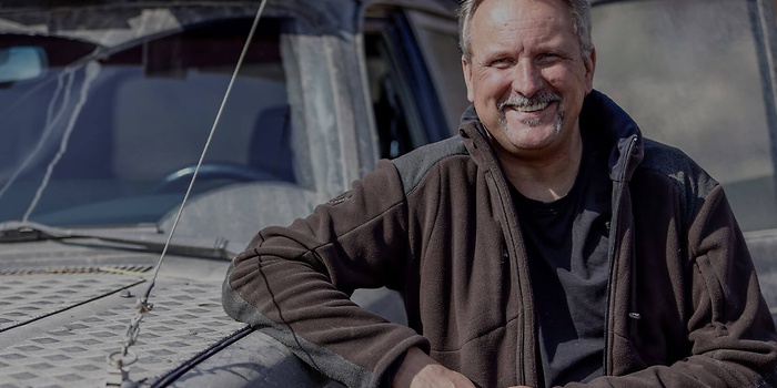 Werkplaatsmedewerker leunt op de achterkant van de auto