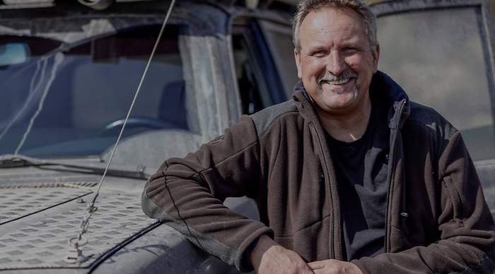 werkplaatsmedewerker leunt op achterkant auto