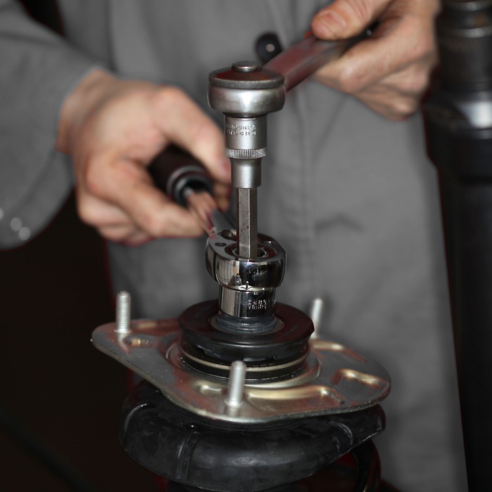 Verwijder de borgmoer op het veerpootlager